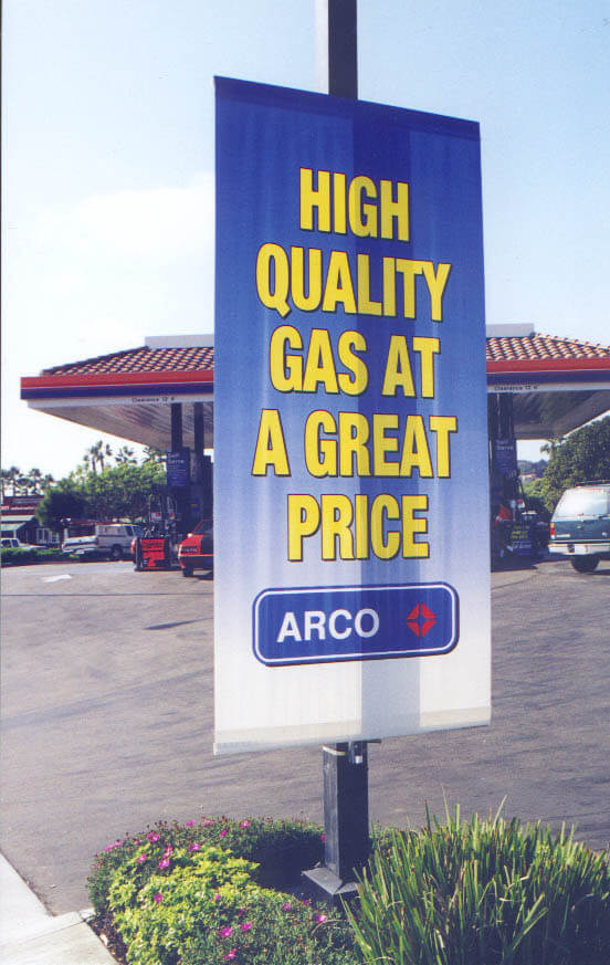 A Sidewalk display using pole displays in front of a gas station using banners and signboards